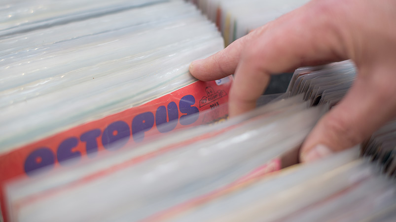 Une main parcourt une sélection de disques pour choisir un titre